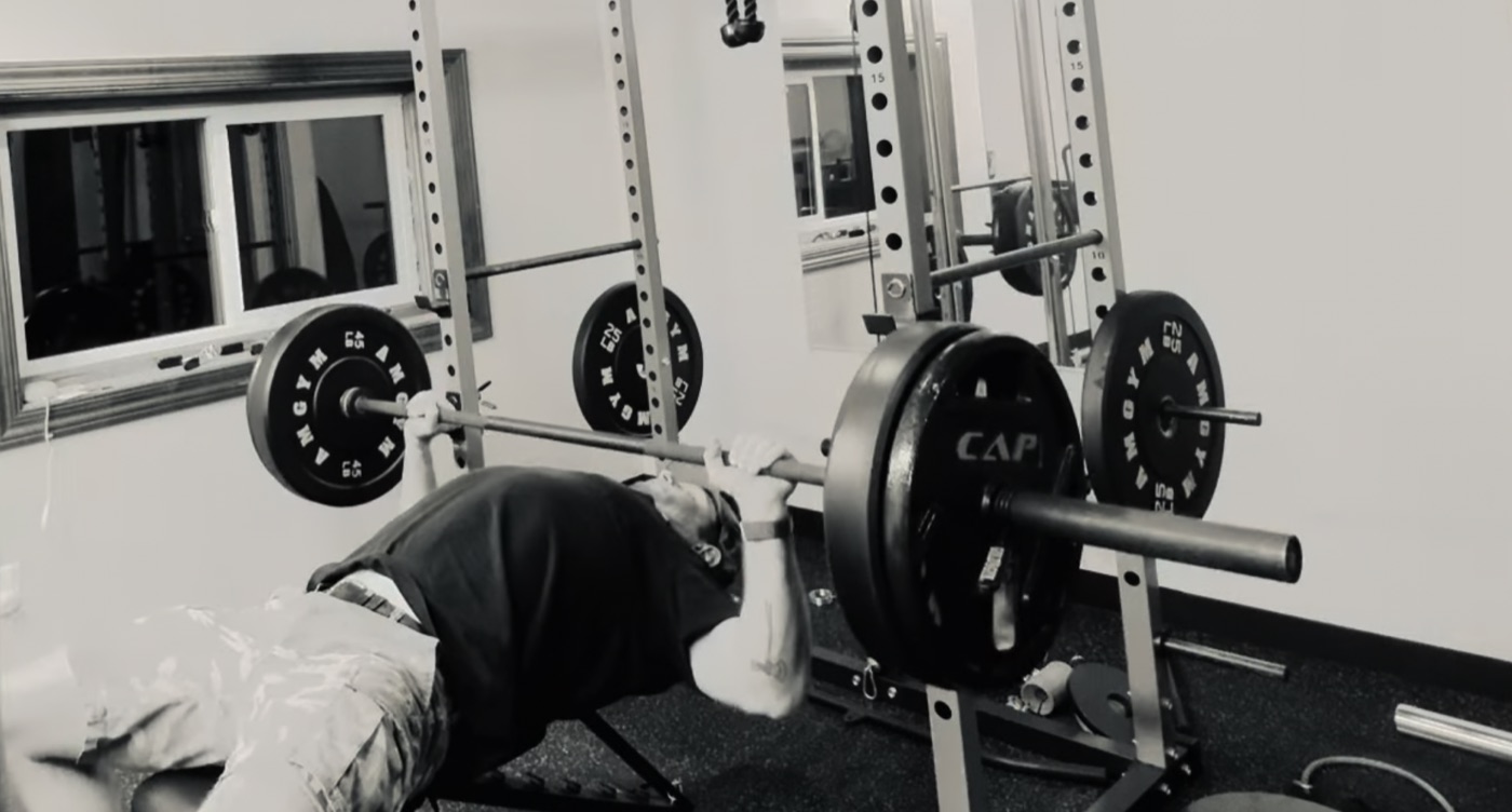 Adam bench pressing in a garage gym.