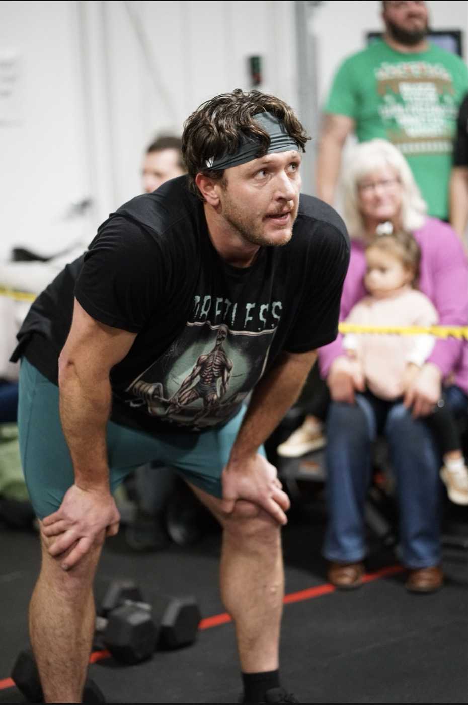 Adam during a workout with family and community behind him.