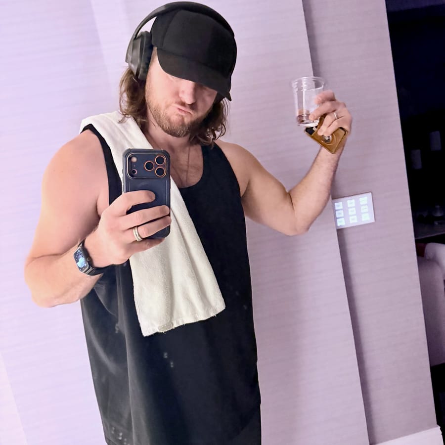 A post-training mirror photo with a black cap, headphones, and gym towel.